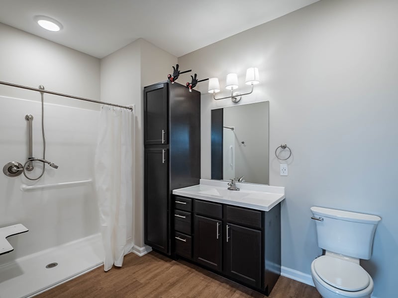 An accessible bathroom in a senior apartment at Cedarhurst of Topeka, featuring safety rails and a roll-in shower