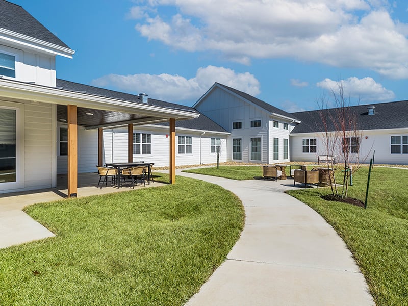 Outdoor green space at Cedarhurst of Topeka with paved walking paths and covered patios