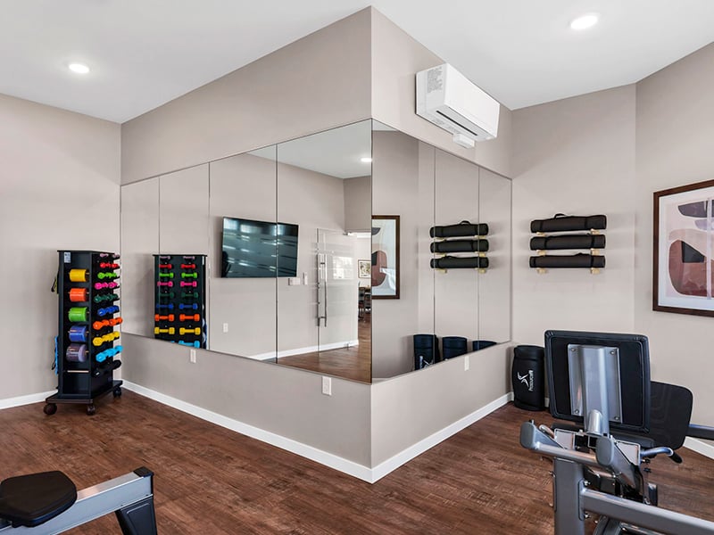 Clubhouse fitness center with free weights at Cedarhurst of Topeka's Independent Living at Cedarhurst Cottages