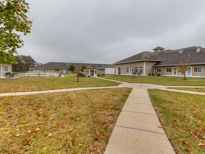 An inviting outdoor space with paved walking paths and a wooden pergola at Cedarhurst of Waterloo senior living community