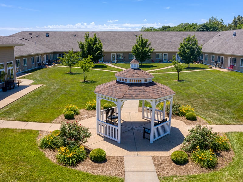 Aerial view of the outdoor green space at Cedarhurst of Waterloo with paved walking paths and a pergola