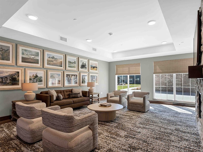 A beautifully designed common area at Cedarhurst of Wentzville, offering a welcoming space for residents to connect, featuring comfortable seating, a fireplace, and a television