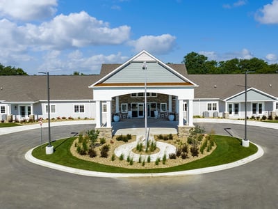 An inviting view of the Cedarhurst of Woodstock  senior living community from the outside, complete with the main building and its distinctive sign