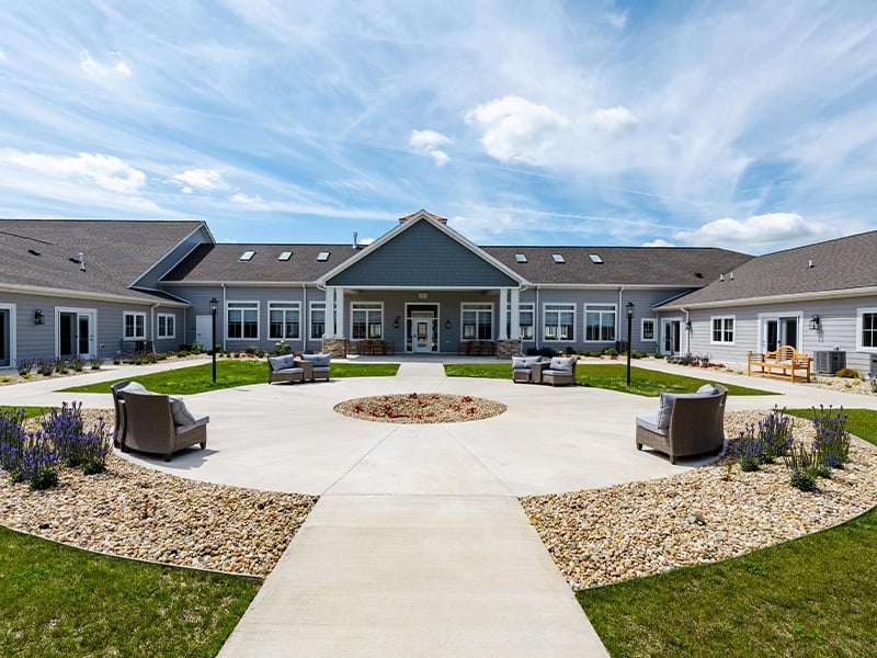 Outdoor green space at Cedarhurst of Woodstock  with paved walking paths and comfortable seating