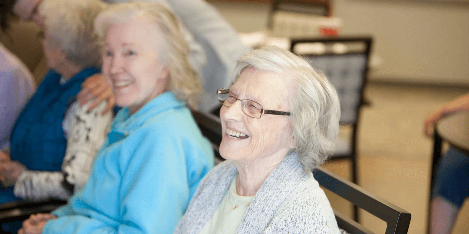 Elderly women in a communal setting, smiling and laughing, conveying warmth and joy