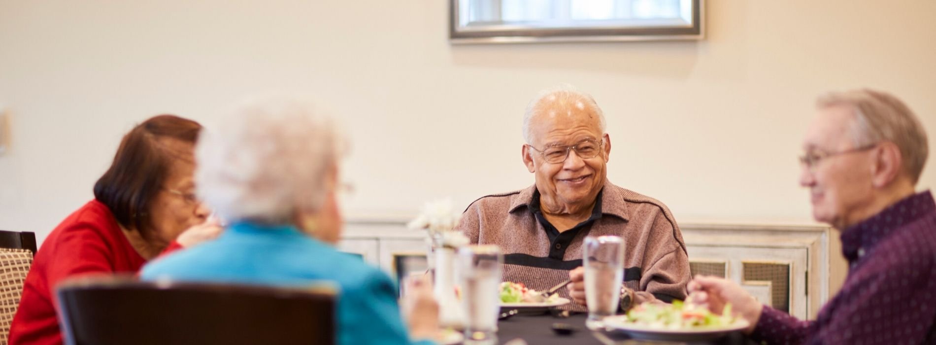 Four senior friends eating in the community restaurant