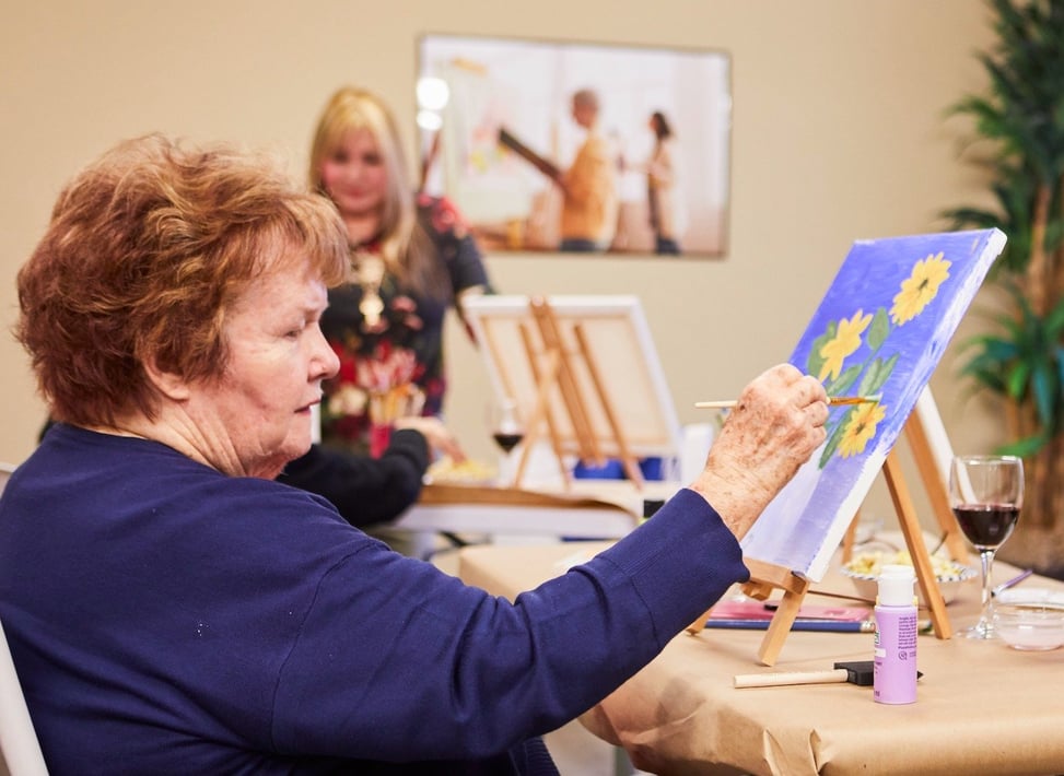 A senior woman painting flowers during a painting class