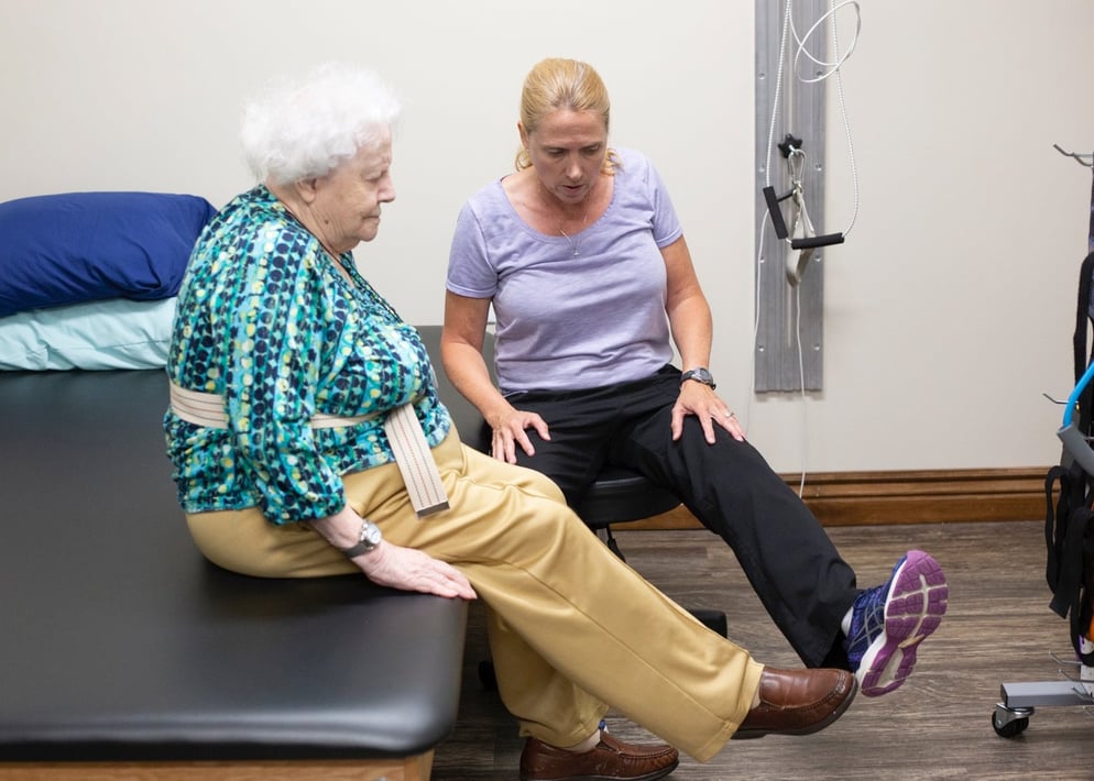 Senior woman performing leg exercises with a physical therapist