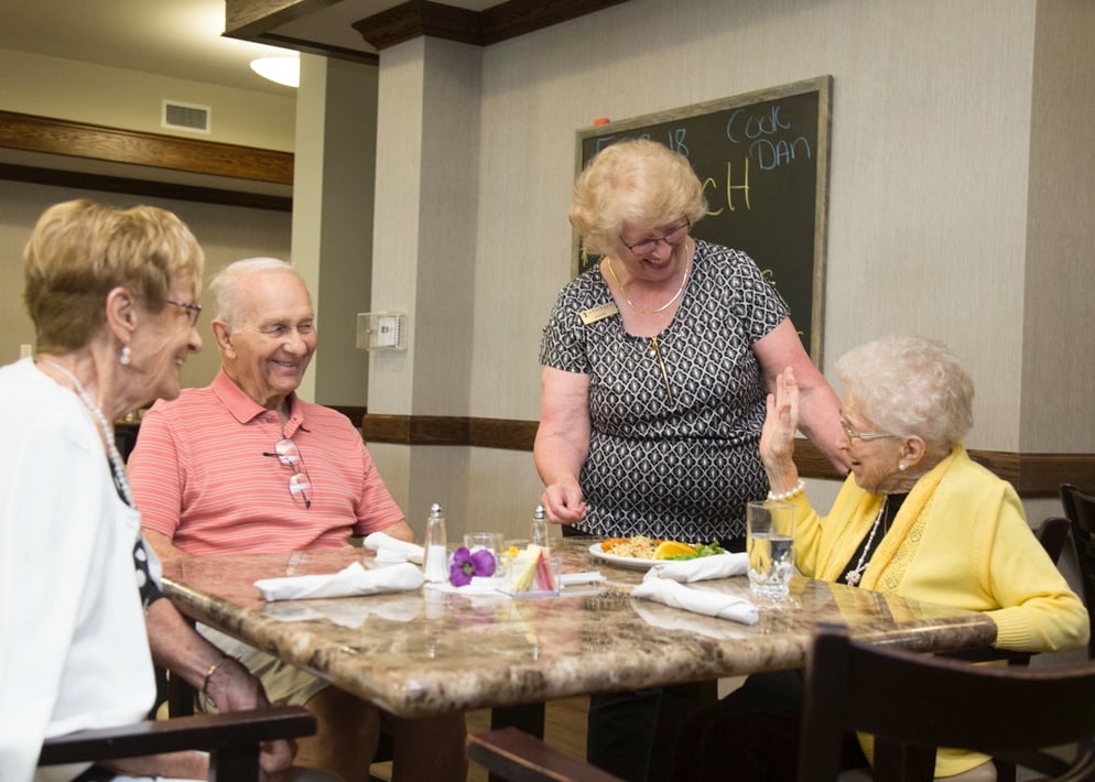 Group of residents dining as a team member serves them