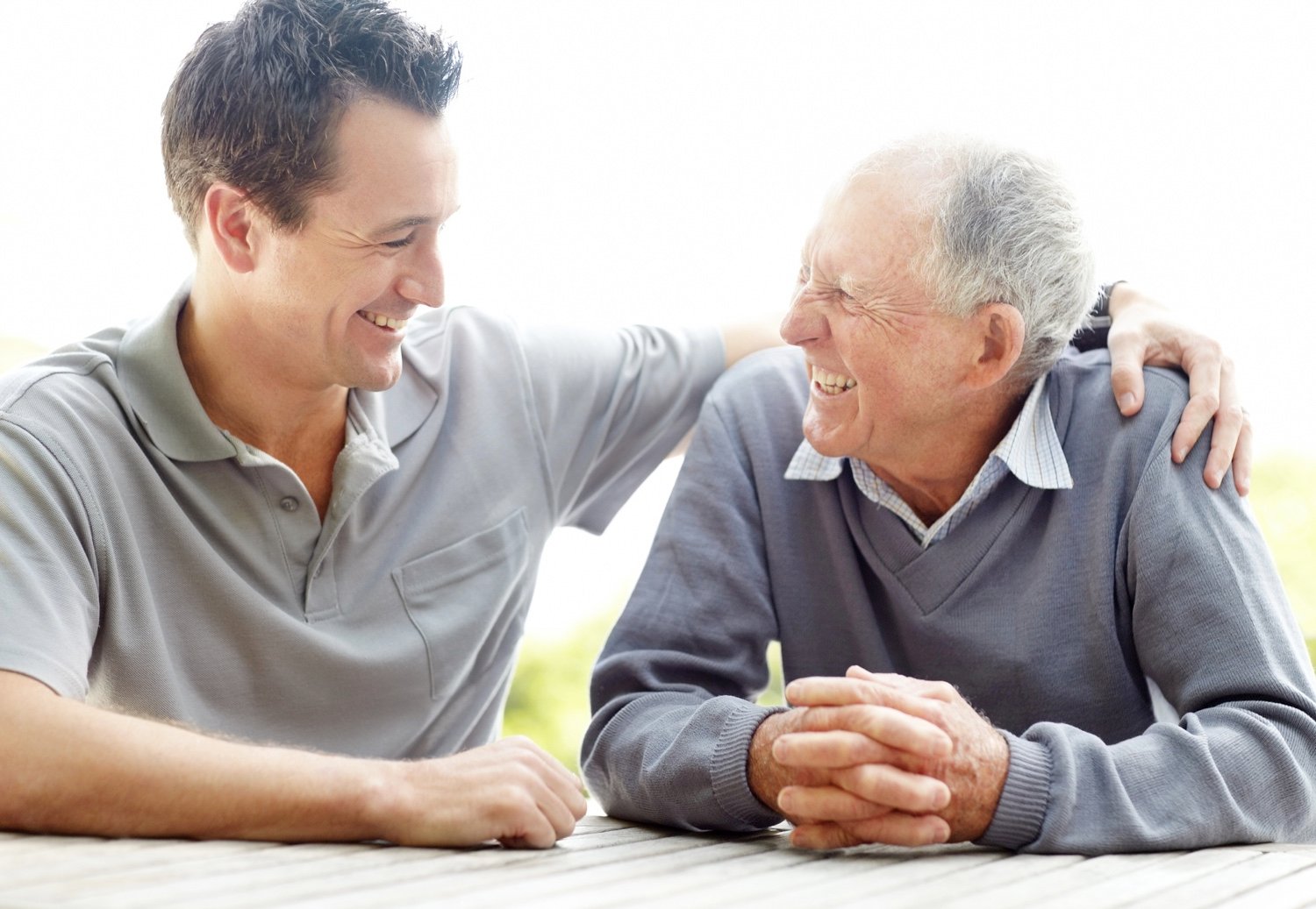 A smiling staff member with his arm around a smiling male senior resident