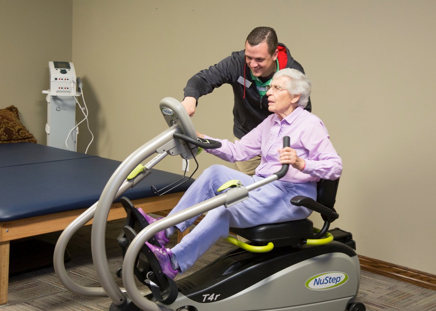 Resident using NuStep machine with physical therapist