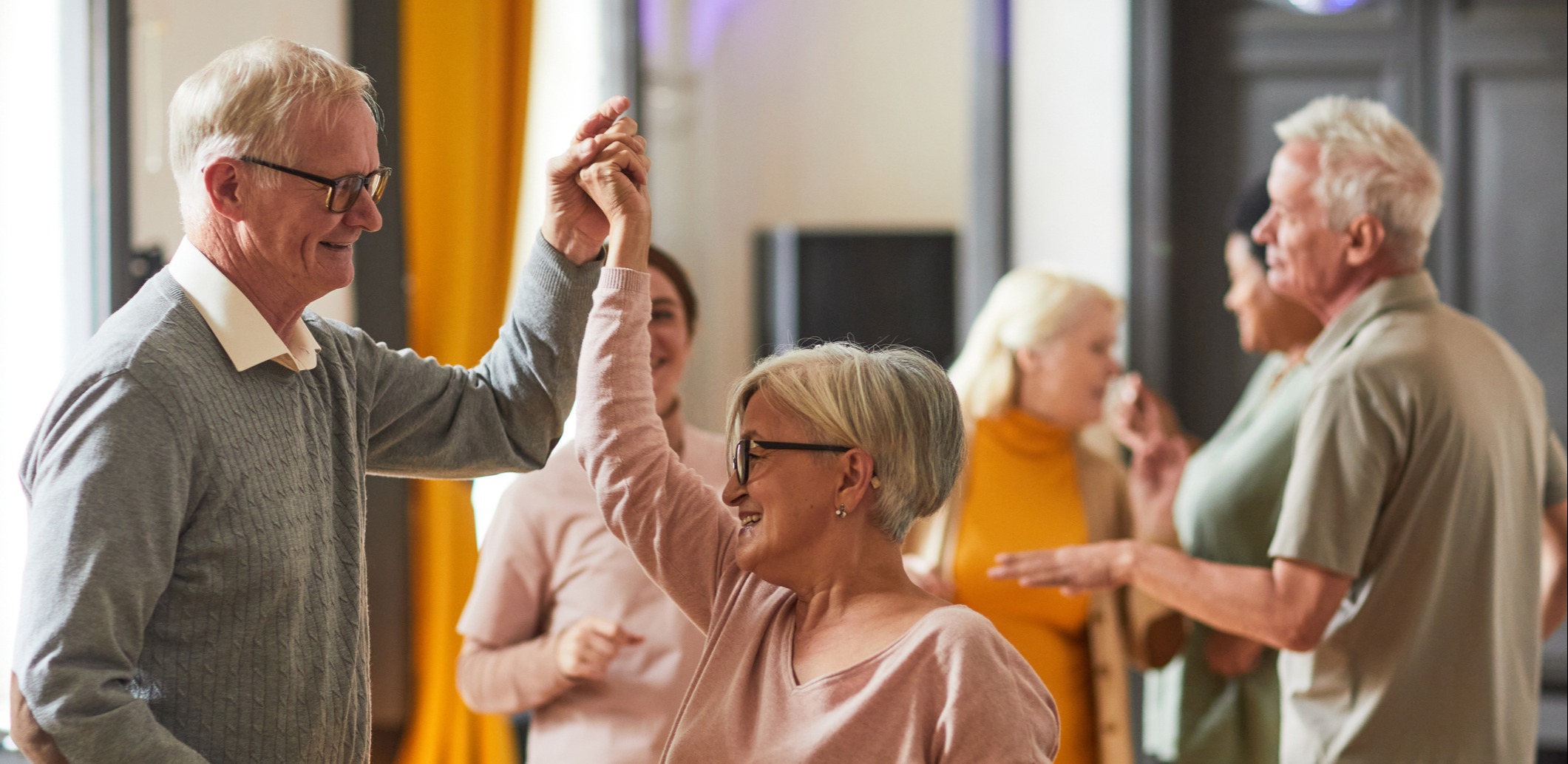 A senior couple dancing among a group of friends