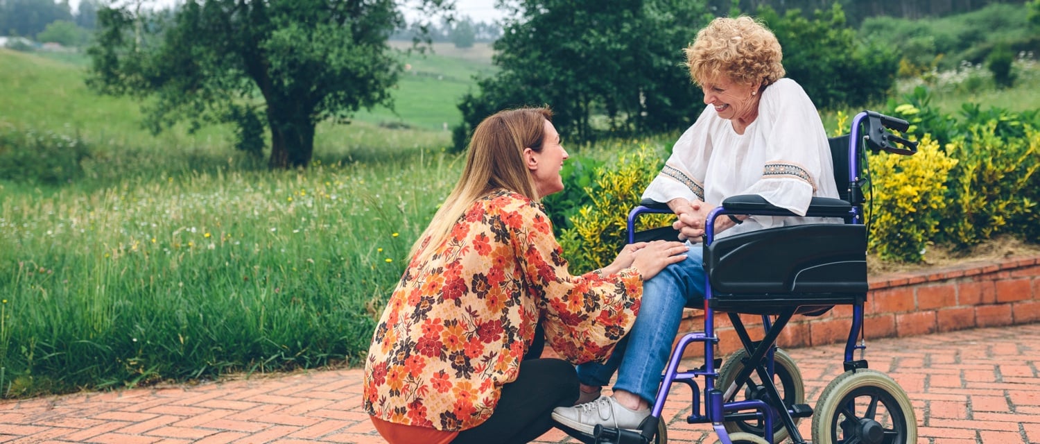 Young woman talking to senior in wheelchair
