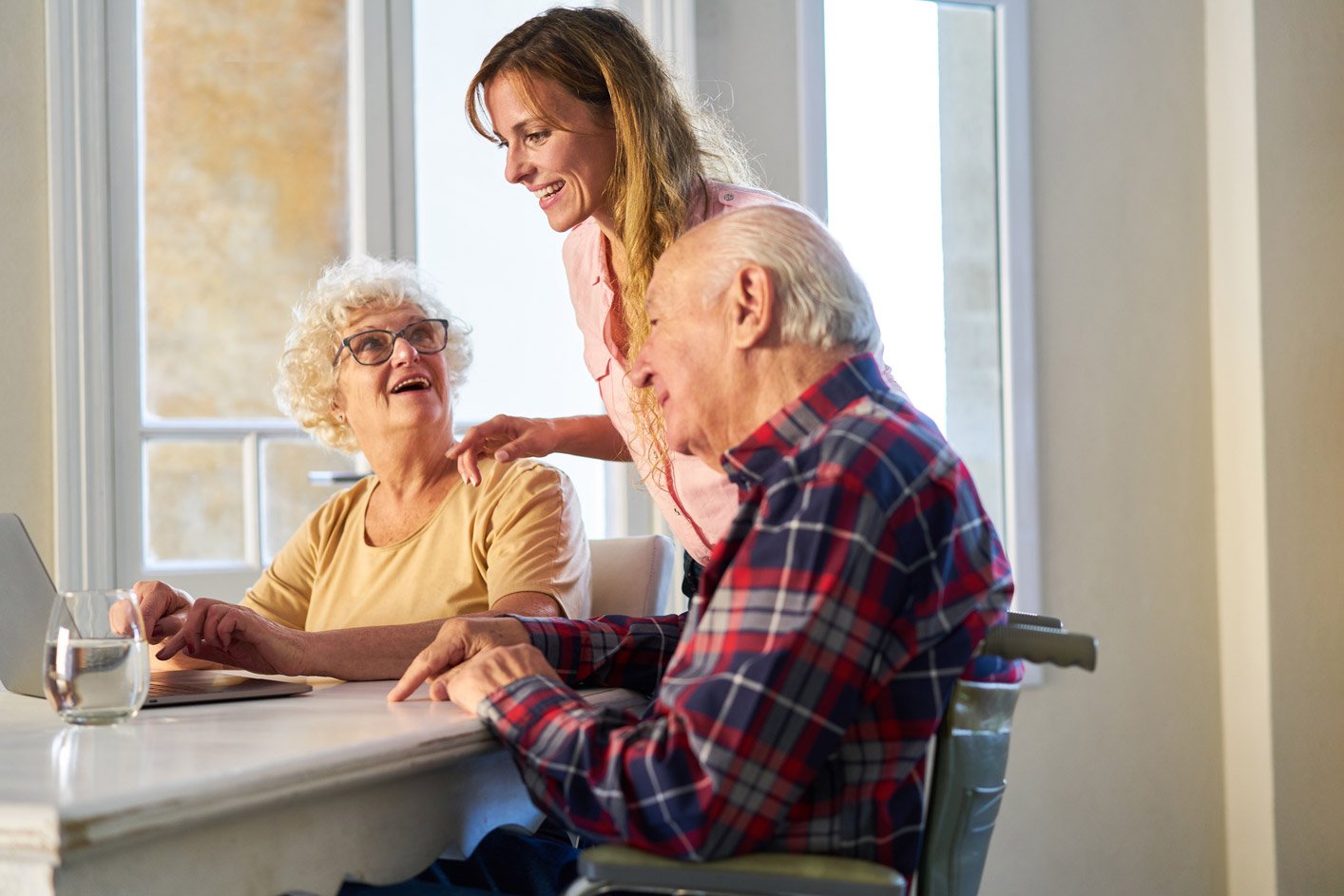 adult daughter helping her parents with something on a laptop computer