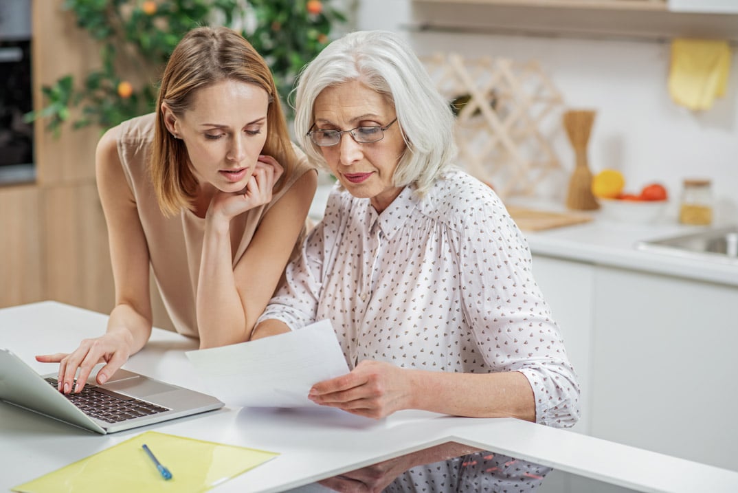 adult daughter helping senior mother with finances