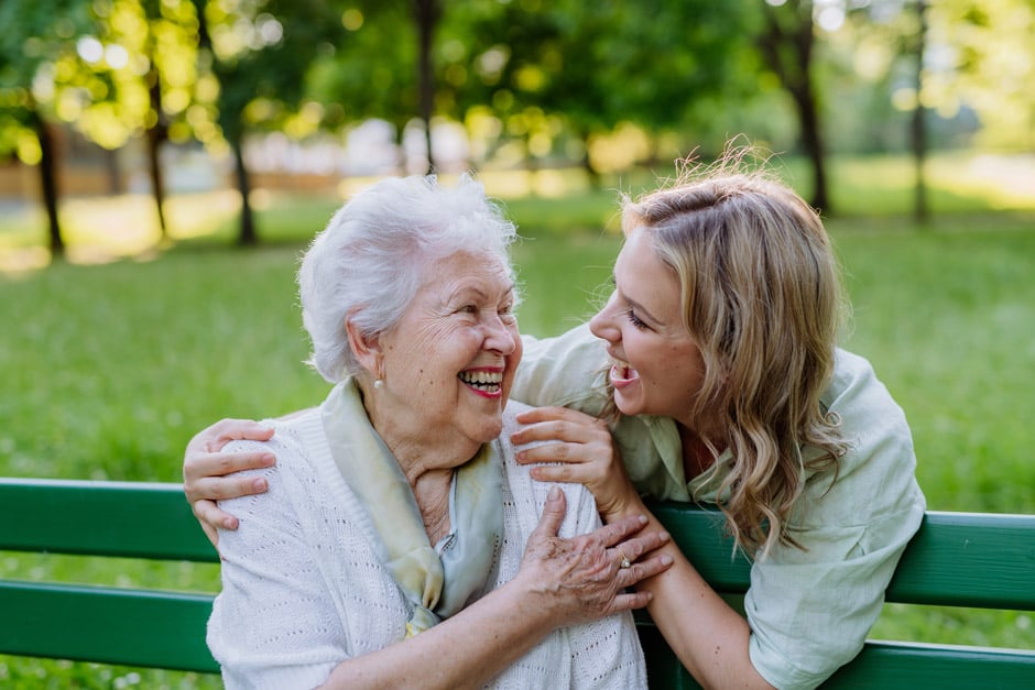 adult daughter smiling at senior grandmother