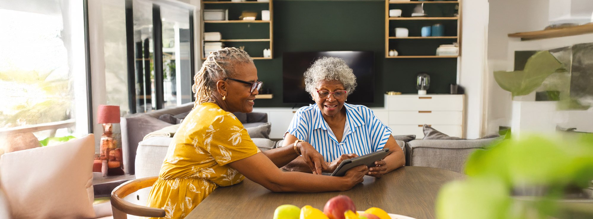 adult daughter helping senior mother with tablet