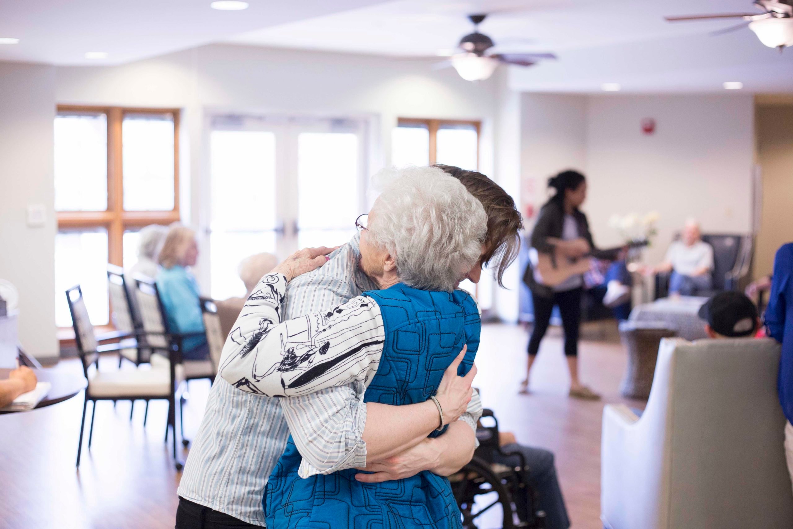 Staff member and senior woman hugging