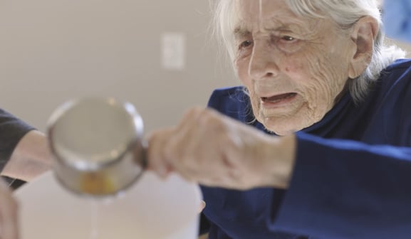 memory care resident using a mesauring cup to bake