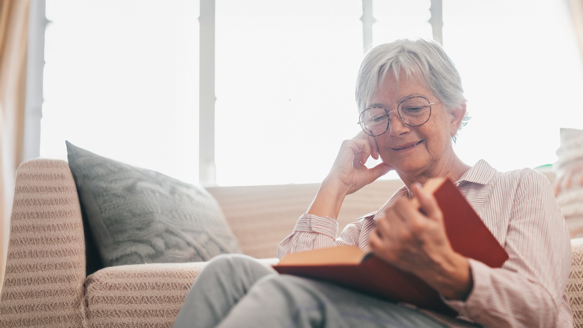 senior living resident enjoying a book in her living room