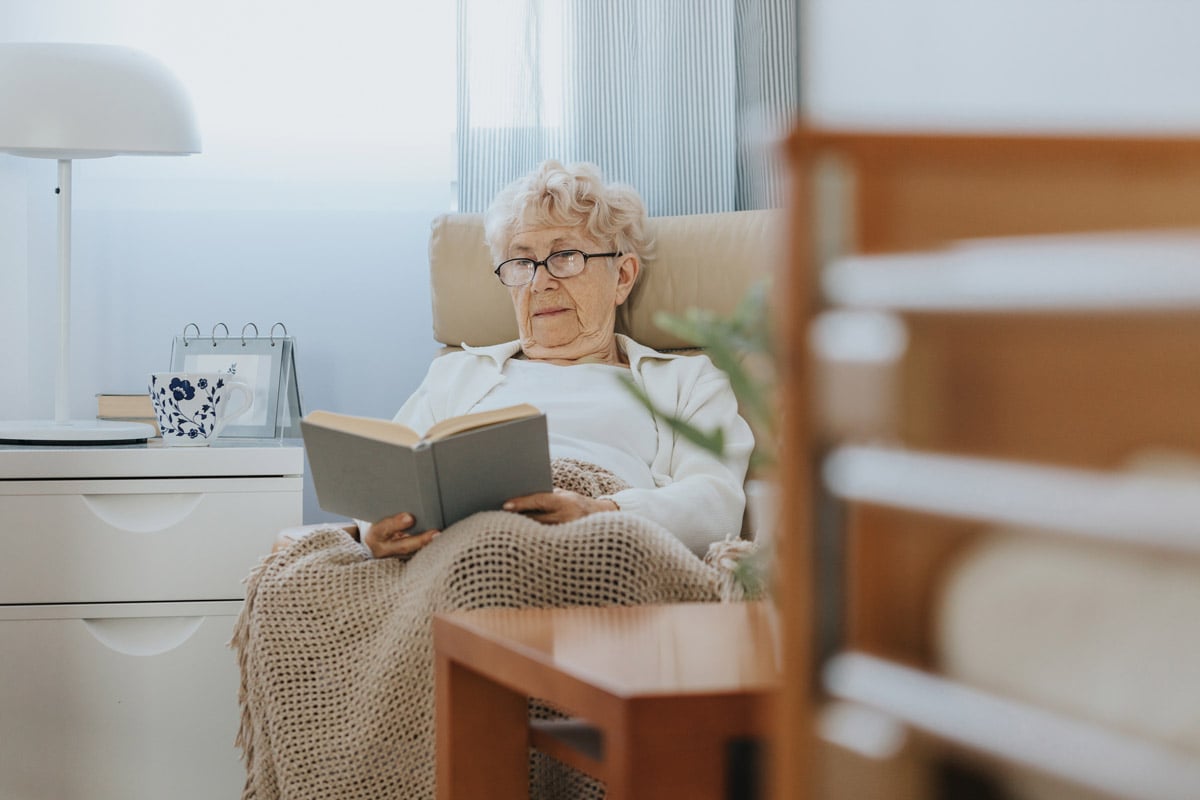 Senior, reading book in recliner chair