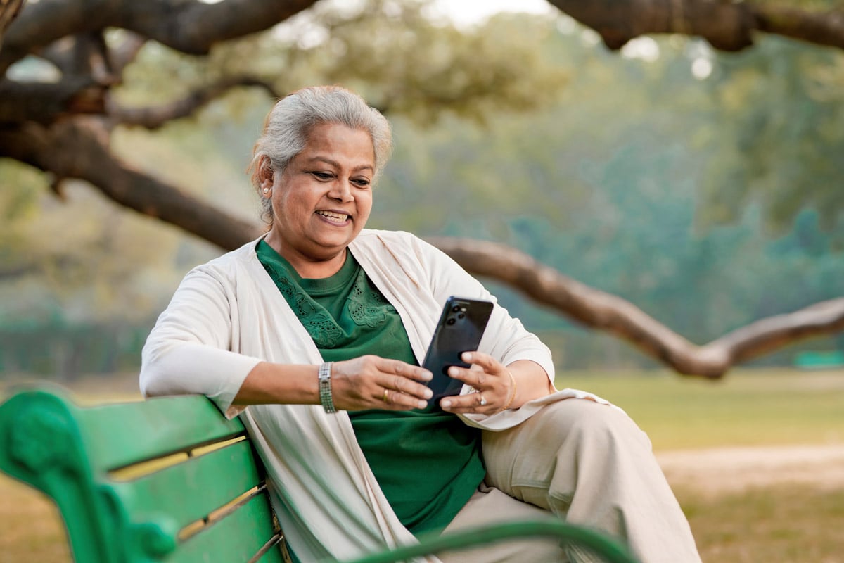 Senior woman sitting on bench outside while looking at phone