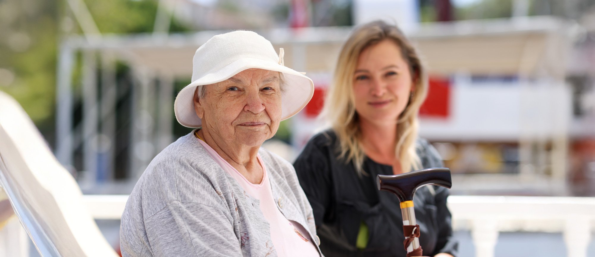 senior woman sitting outside with caretaker