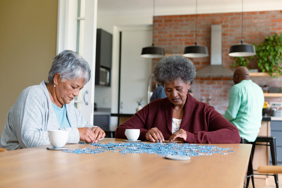 Seniors putting together a blue puzzle on dining room table