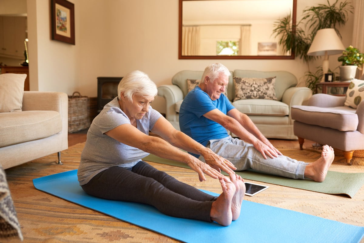 seniors stretching on exercise mats in living room