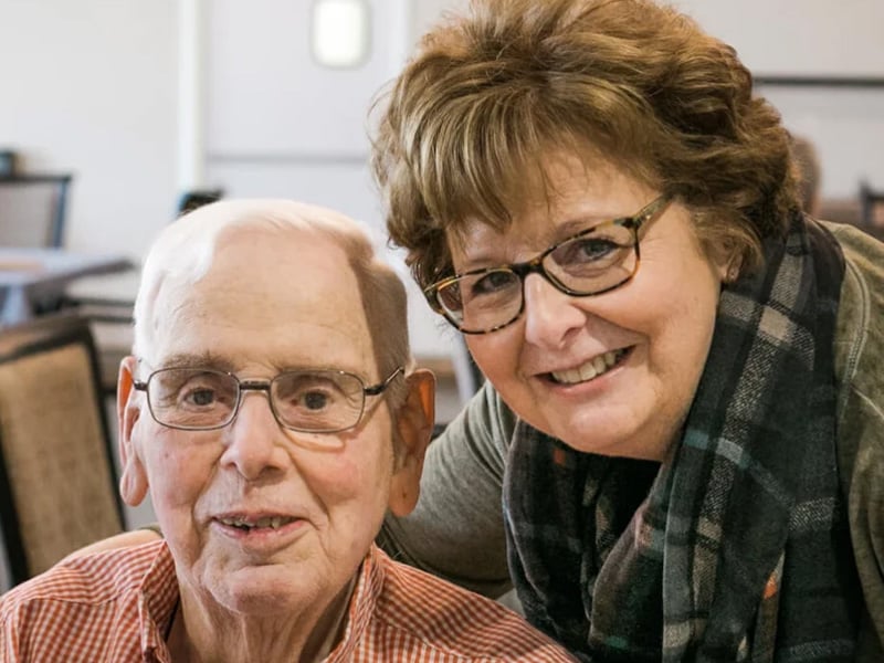 Senior living resident smiling at the camera with staff member