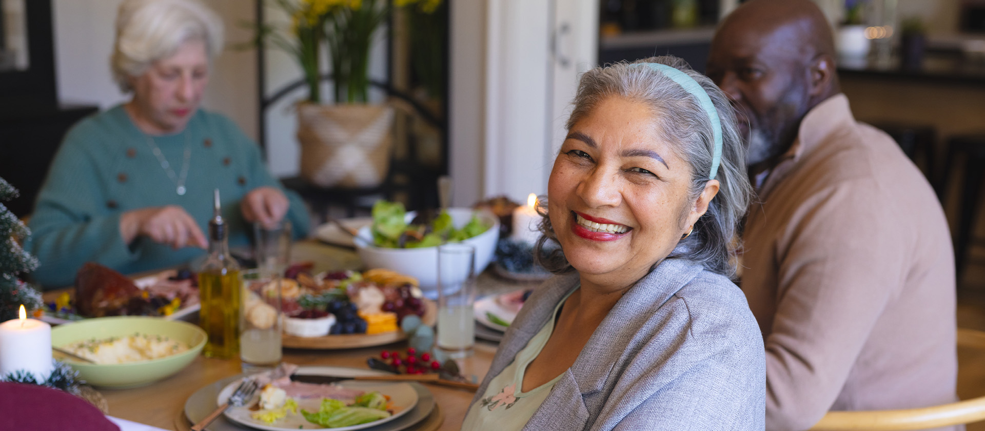 senior woman celebrating with friends at dinner in sunny dining room