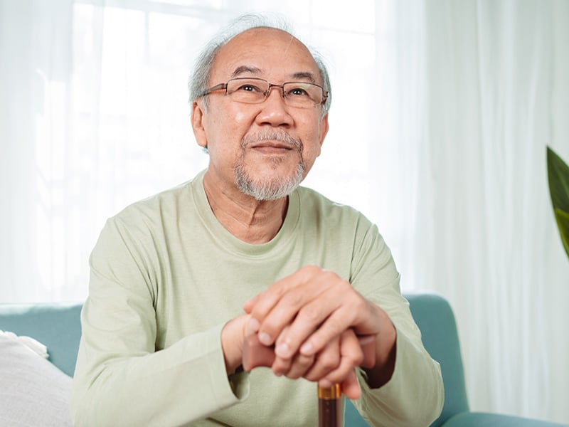 Senior man smiling at the camera holding a cane
