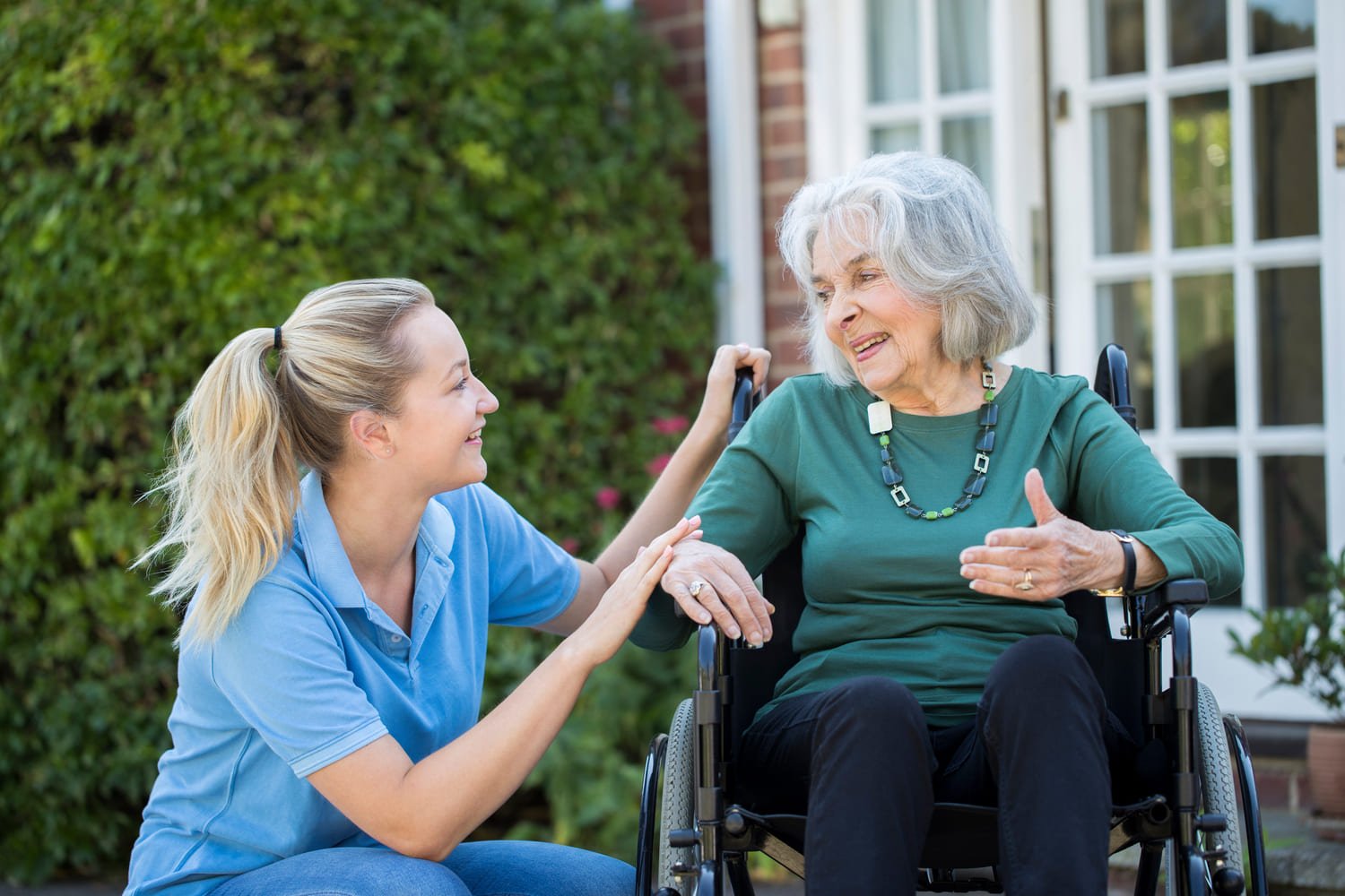 caregiver smiling with a senior woman in a wheelchair 