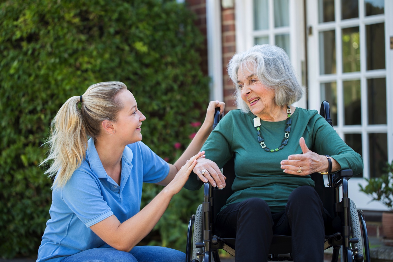 Carer Pushing Senior Woman In Wheelchair 