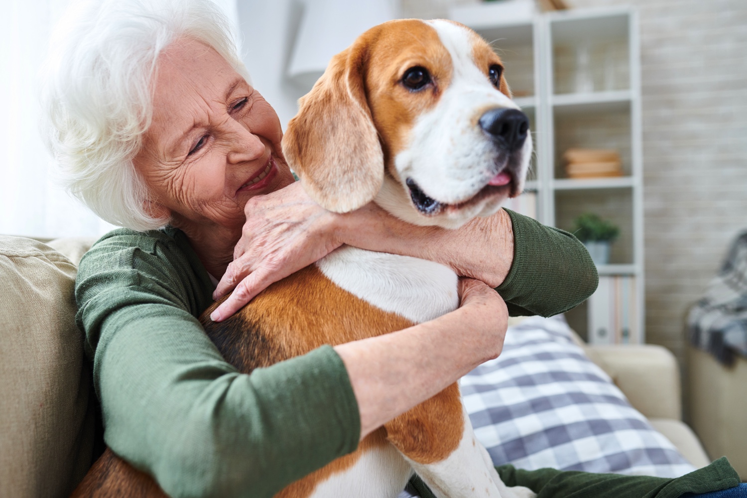 Senior woman hugging a dog in a senior living community apartment.