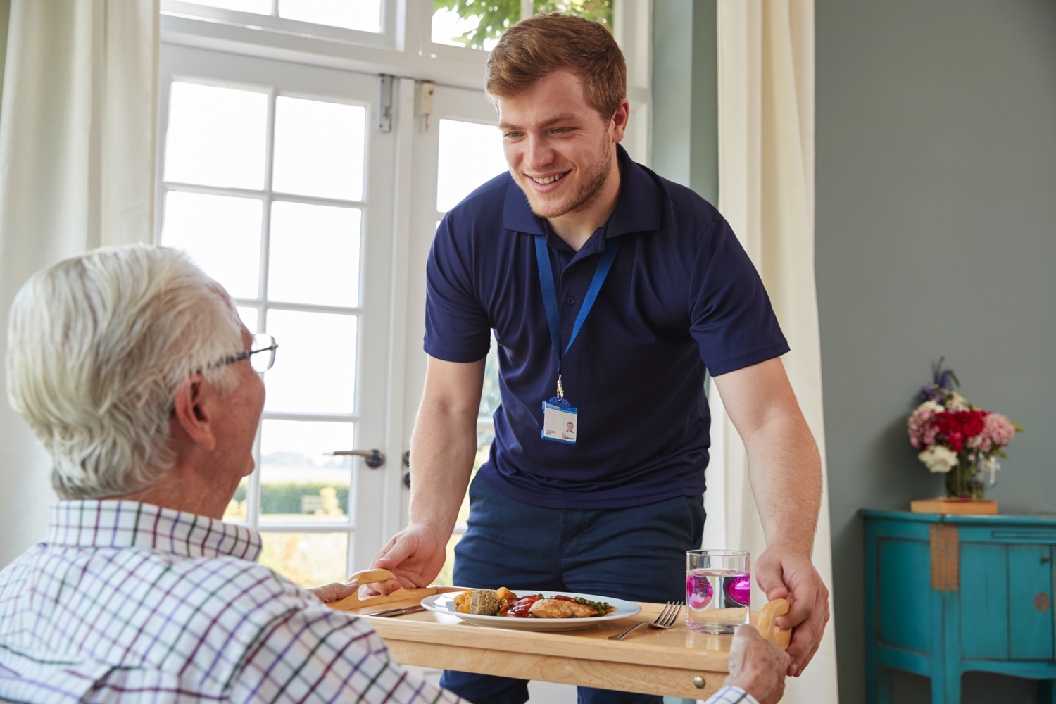 Staff member bringing dinner for senior man
