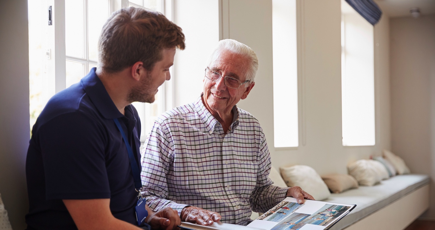 Senior man and staff member looking at a photo album together