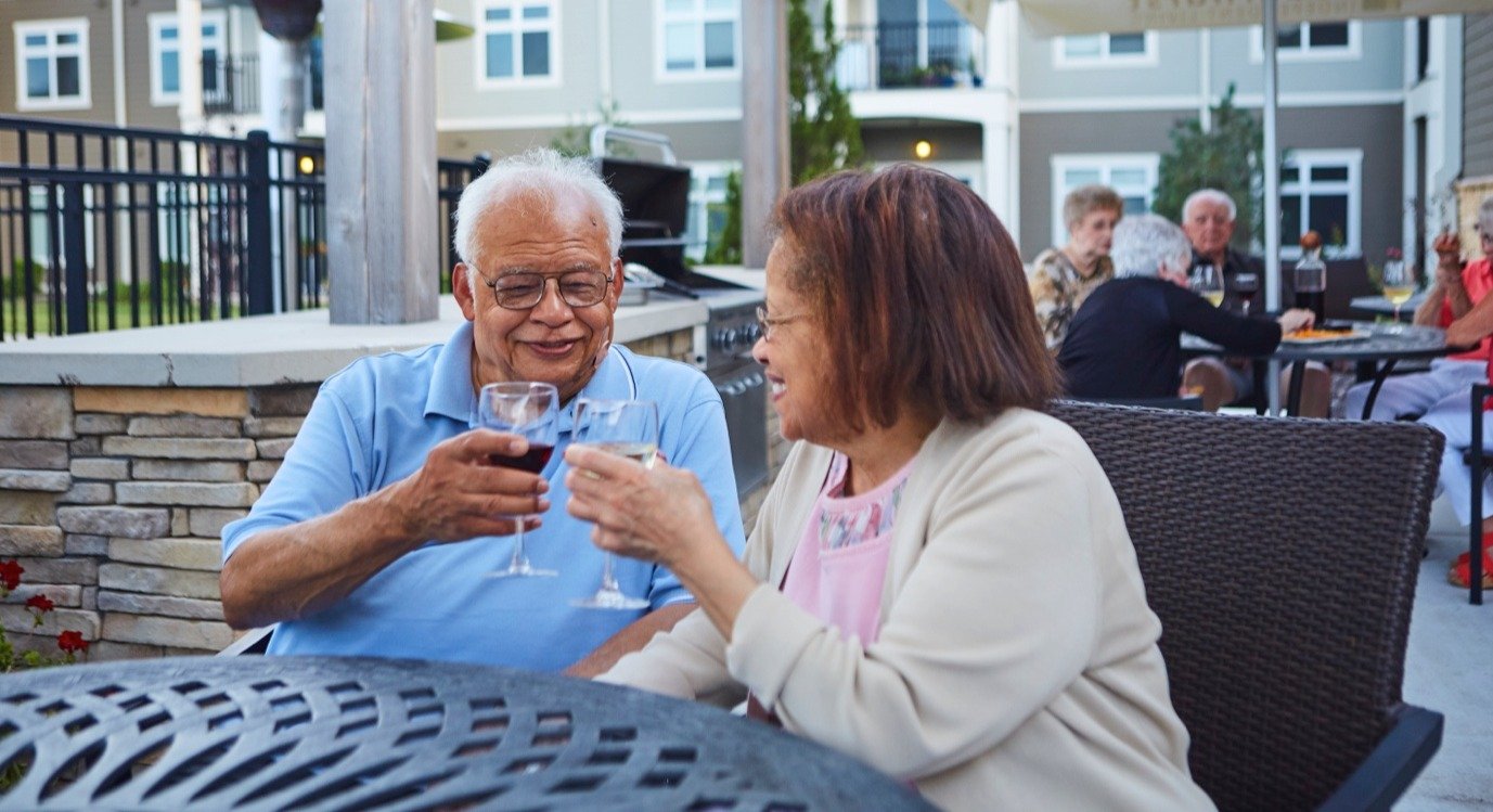 Senior couple toasting with drinks at a patio table