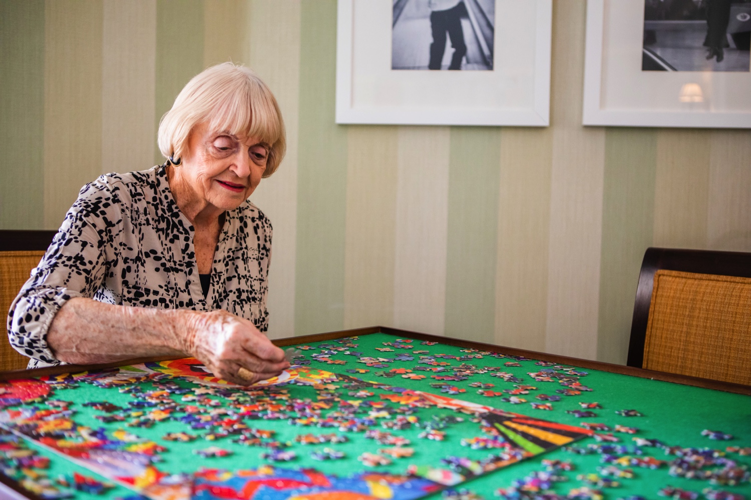 Senior woman completing a jigsaw puzzle at a table