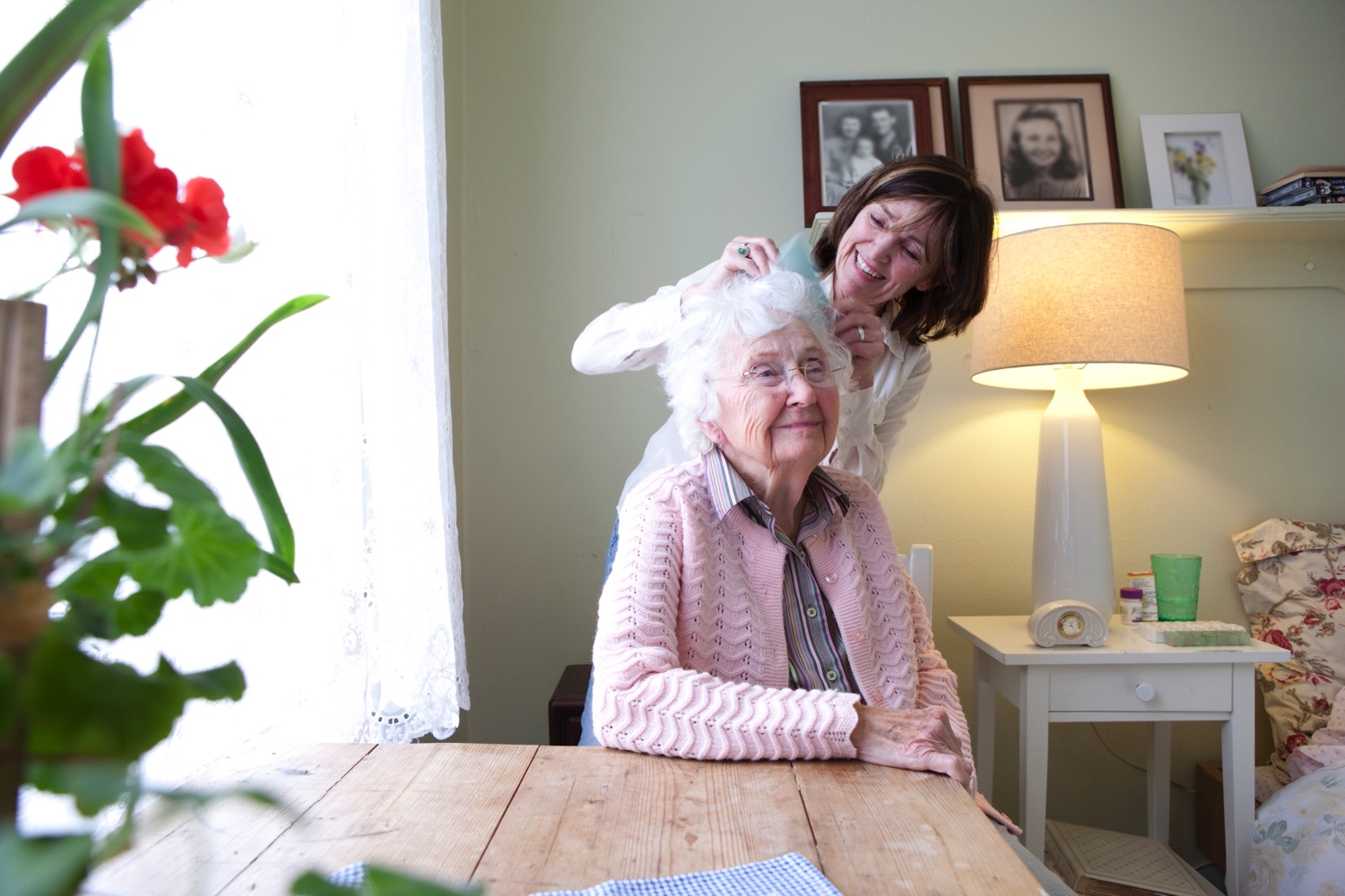 A staff member helps style a senior resident's hair