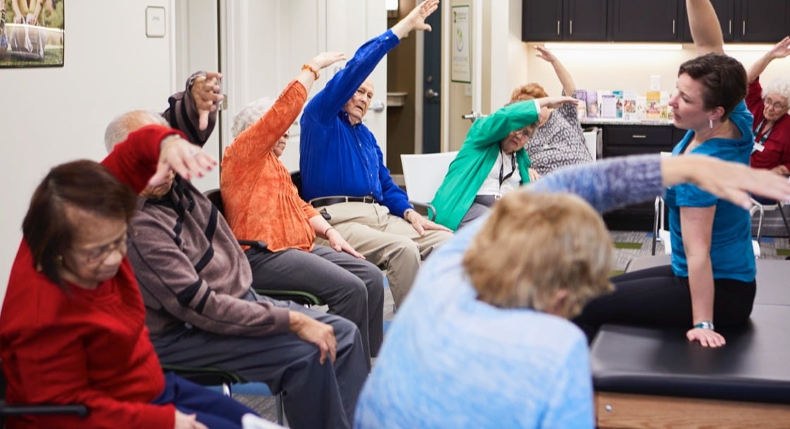 A group of seniors participating in a group exercise class led by an instructor
