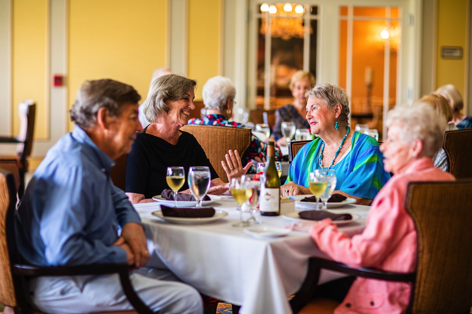 Four senior friends dining together in the community dining room