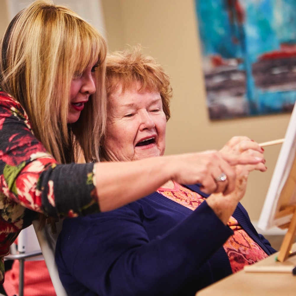 Caregiver painting with a woman resident