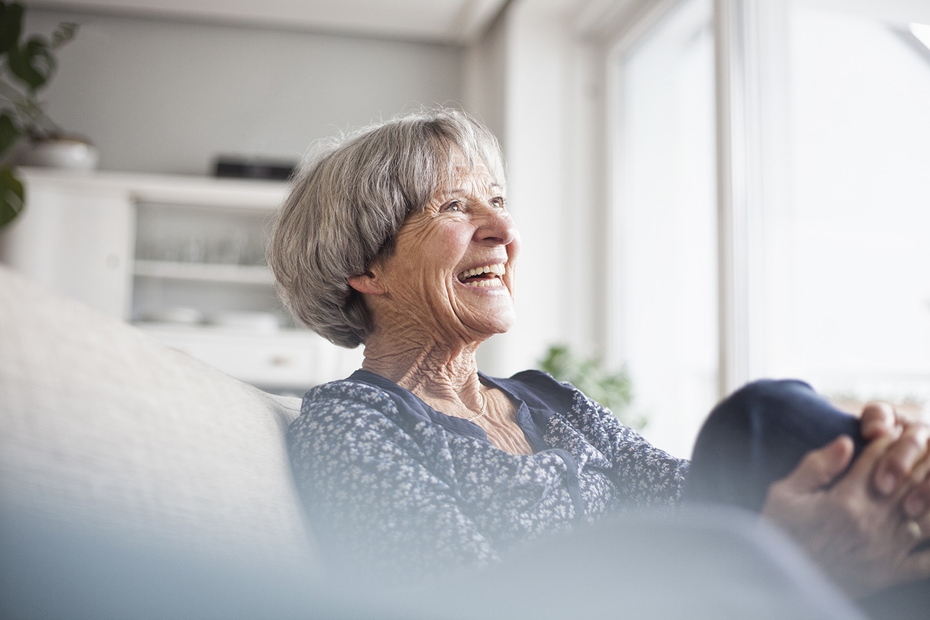 A senior woman smiling up at a visitor