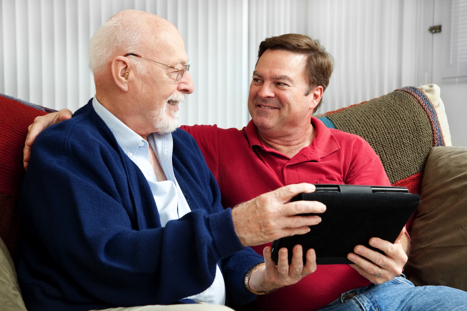 Staff member helping senior man with a digital tablet