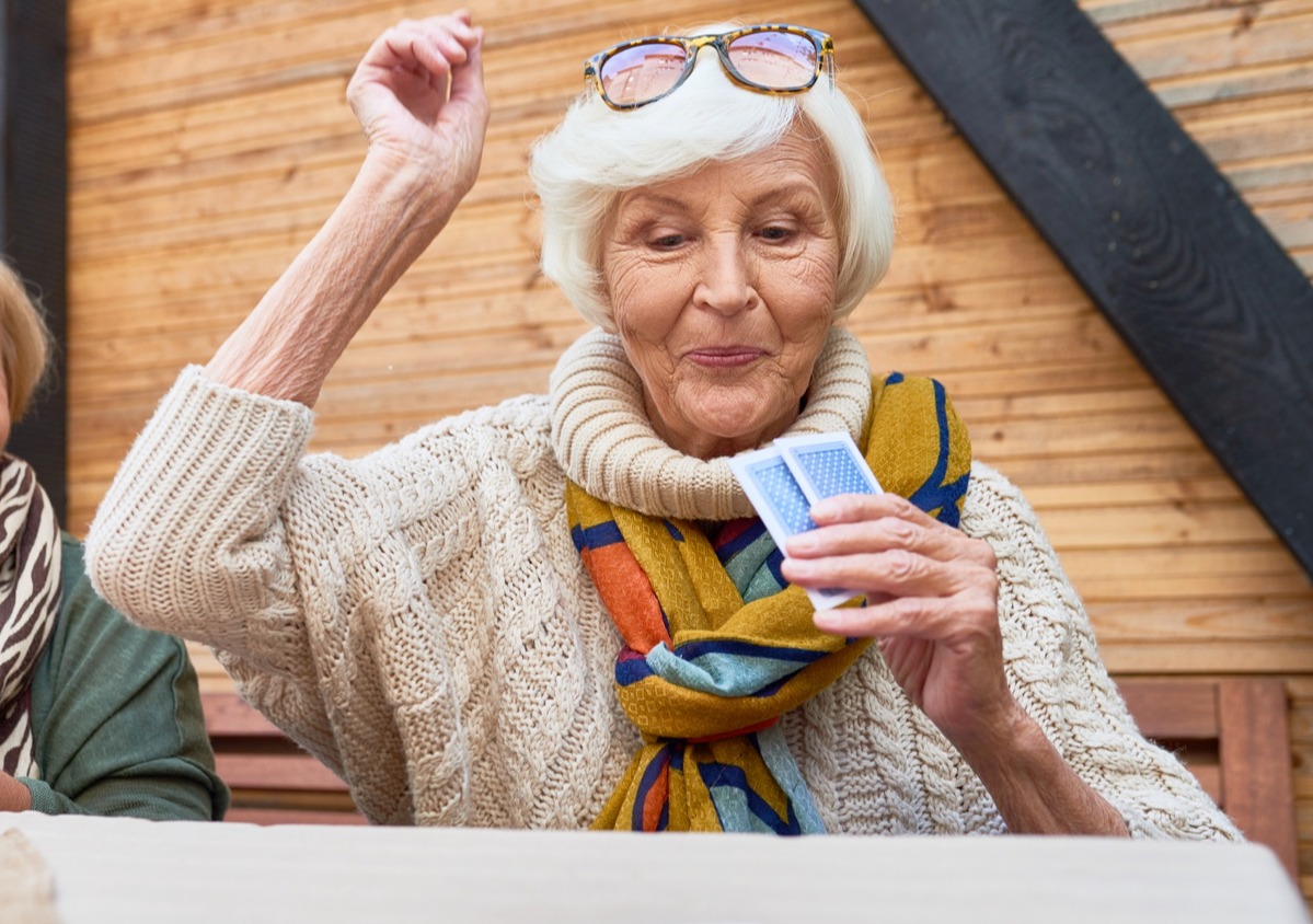 Happy senior woman winning a card game