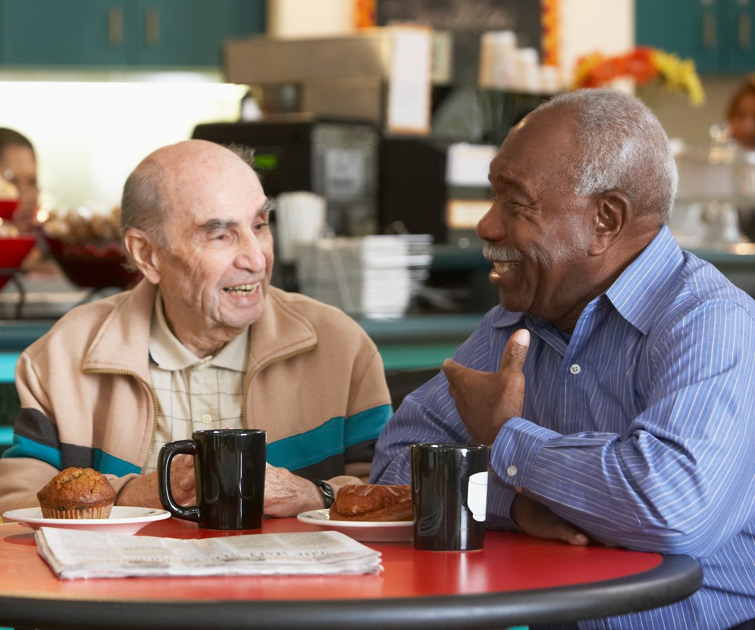 Two senior men conversing over coffee in a dining room