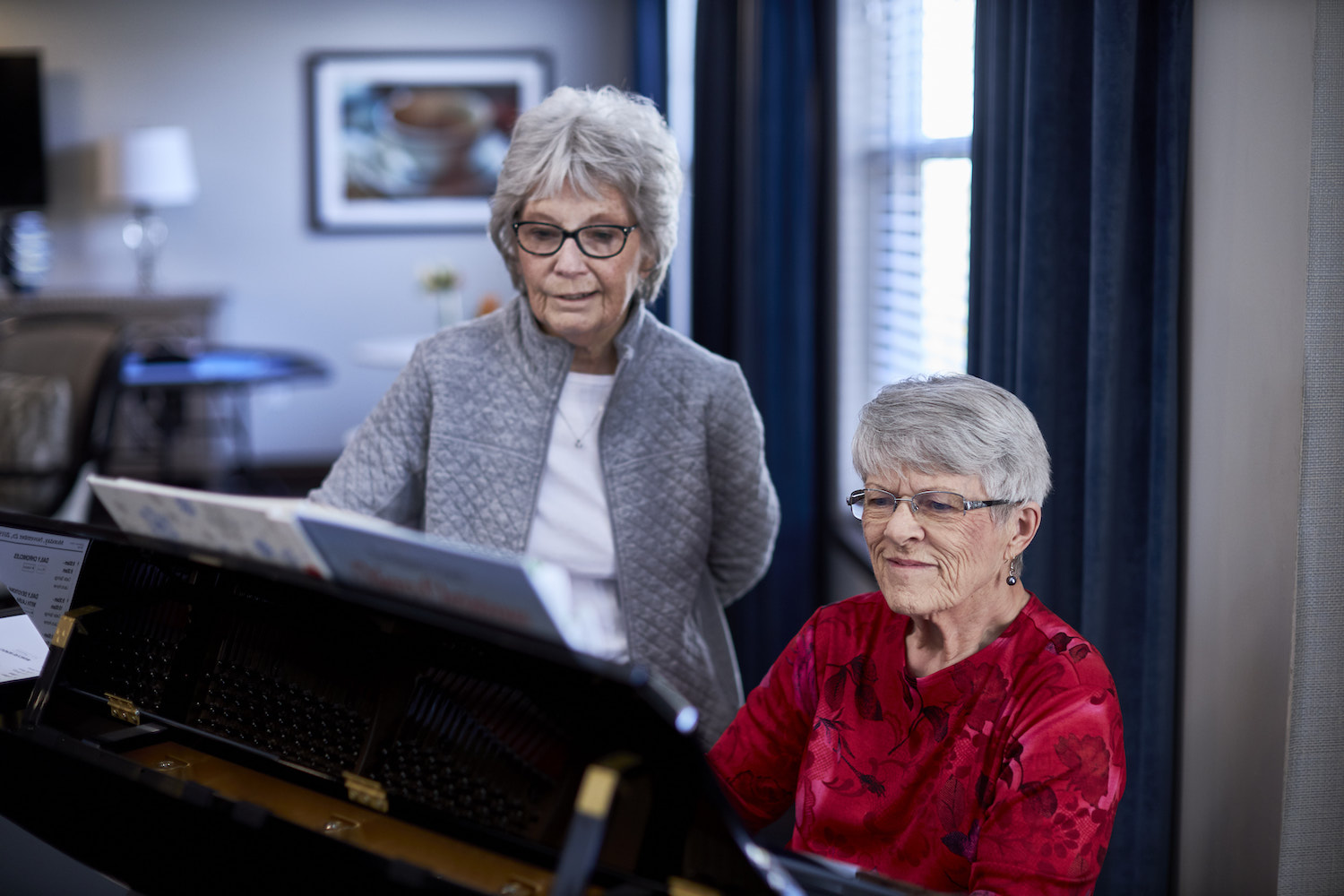 Senior woman playing the piano as another woman sings along