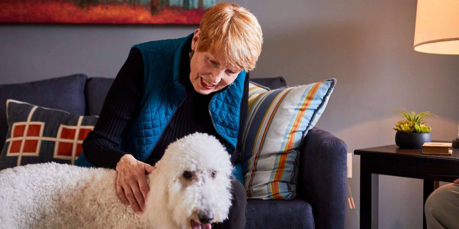 Senior resident petting her dog in a community that welcomes pets for seniors