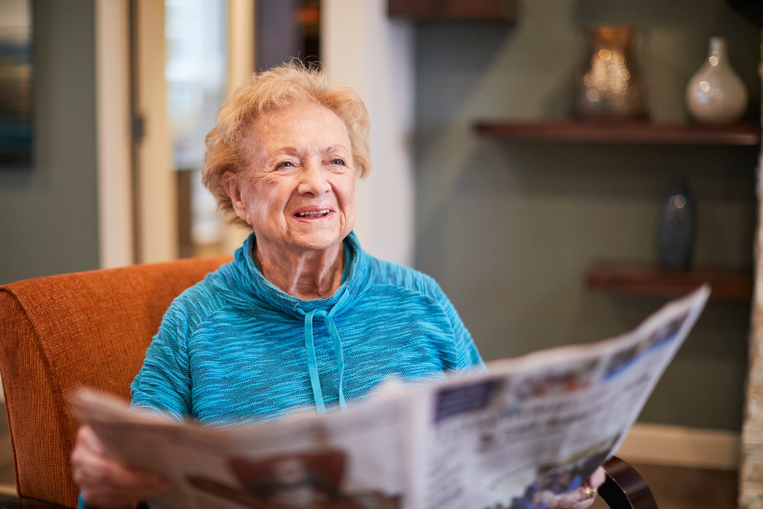 Resident reading a newspaper in a living room chair